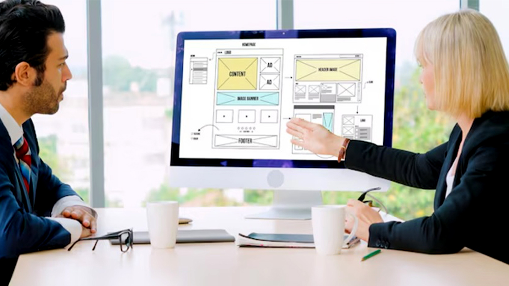 زن و مردی در حال بررسی قالب و طراحی سایت روی مانیتور