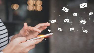 دست در حال تایپ روی گوشی با المان‌های ایمیل گرافیکی معلق اطراف آن