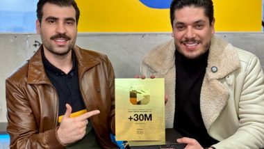 سینا فرحی در حال اشاره کردن به یک لوح طلایی با عبارت +۳۰ میلیون روی آن در کنار یک فرد دیگر